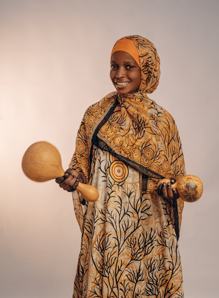 Portrait of a woman smiling while holding traditional African shakers.