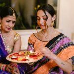 Mother and daughter performing a Diwali ritual with a lit puja plate, showcasing traditional Indian culture.